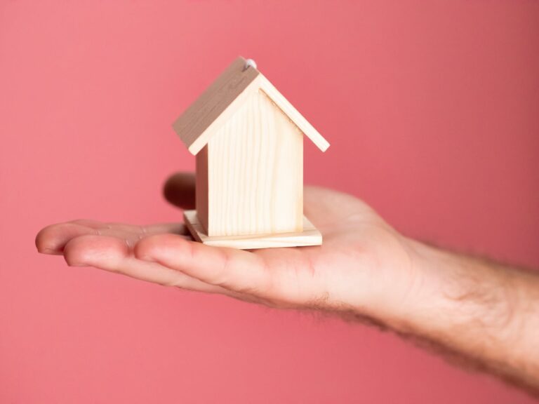 person holding brown miniature wooden house