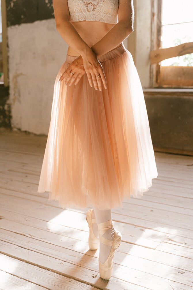 a woman wearing tutu and pointe shoes standing on a wooden floor